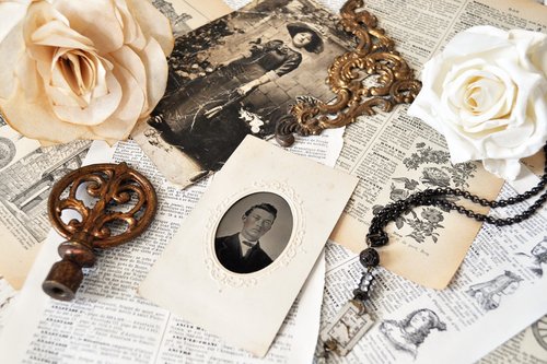 Ruusuja, vanhoja valokuvia ja tavaroita vanhojen sanomalehtien päällä.