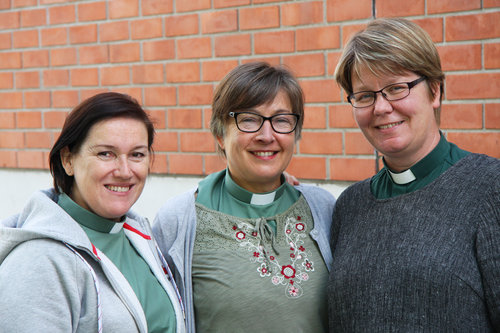 Kolme diakoniatyöntekijää seisovat vierekkäin ja hymyilevät.