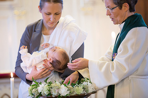 Pappi kastaa kummin sylissä olevan tummahiuksisen lapsen.